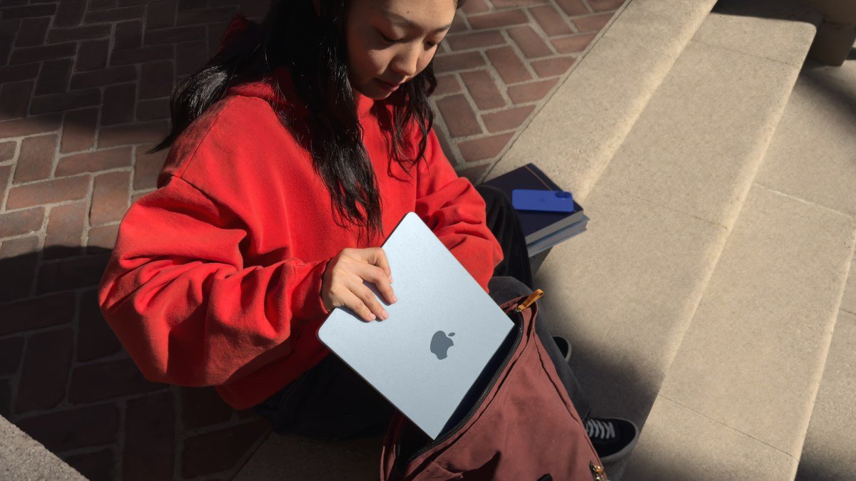 young woman putting Apple MacBook Air into a satchel
