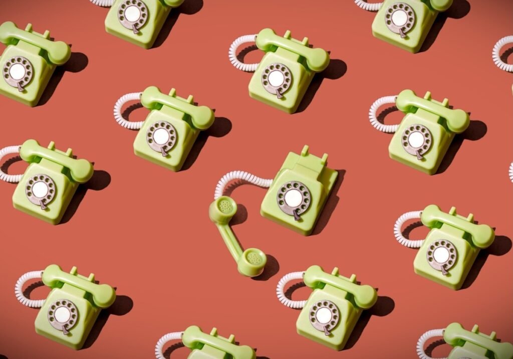 High angle view of some vintage green rotary telephones arranged on a brown background, showcasing retro communication technology with a nostalgic and artistic flair