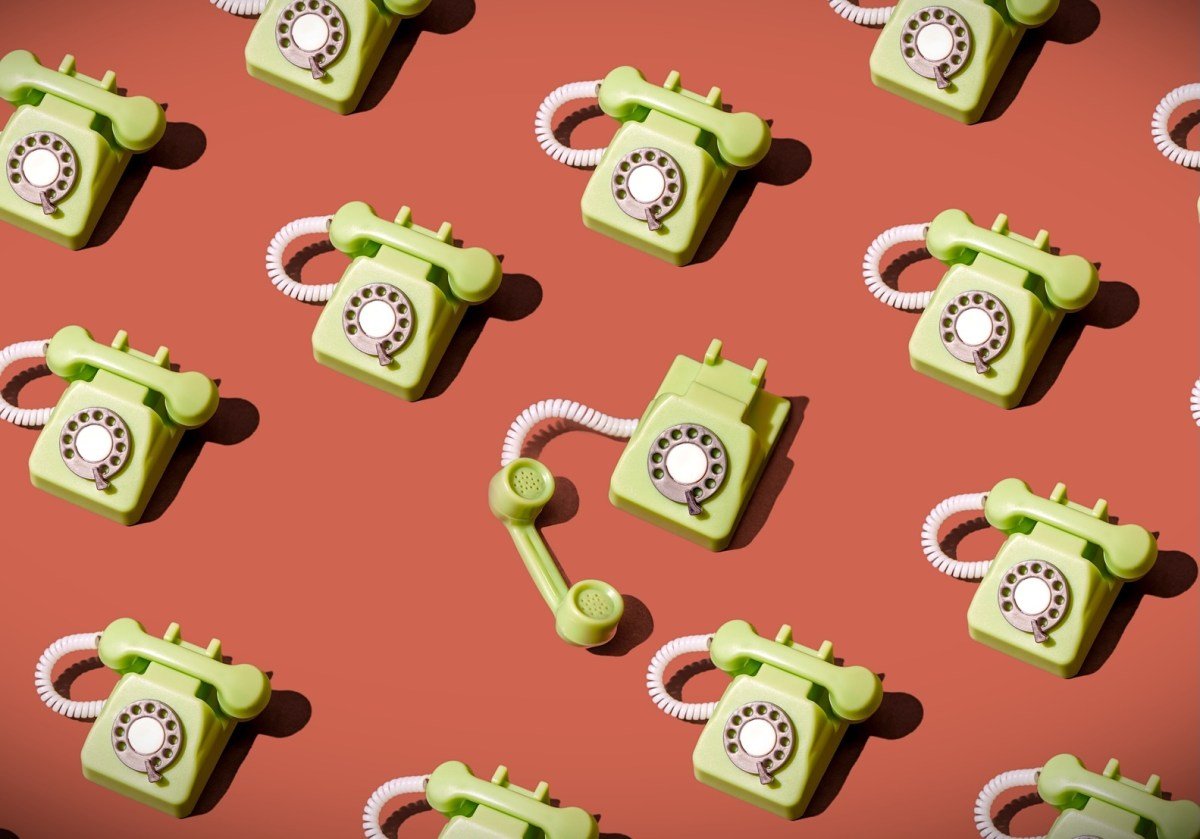 High angle view of some vintage green rotary telephones arranged on a brown background, showcasing retro communication technology with a nostalgic and artistic flair