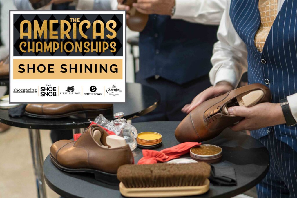 A person holds a polished brown leather shoe while surrounded by shoe shining supplies, including brushes and polish containers.
