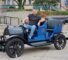A person sits in a vintage black and blue car with the word "Sandusky" displayed on the front.