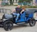 A person sits in a vintage black and blue car with the word "Sandusky" displayed on the front.